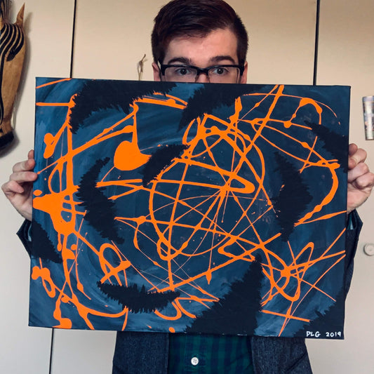 Artist holding the original Darkness Conspires 1 painting with orange drips on blue canvas