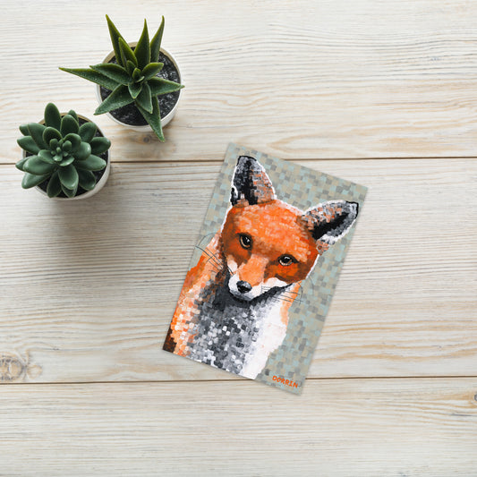 Postcard with a fox design on a wooden surface with small plants.