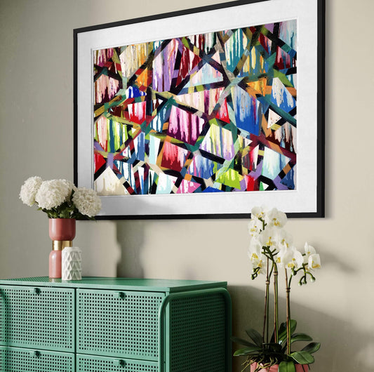 Framed Intersections abstract print angled above a green cabinet with orchids