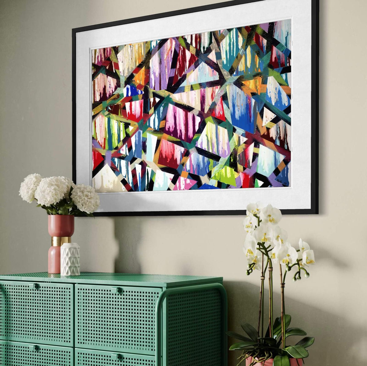 Framed Intersections abstract print angled above a green cabinet with orchids