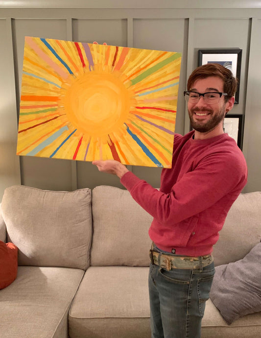 Dorrin Gingerich holds the original Mr. Sunshine acrylic sun painting on canvas