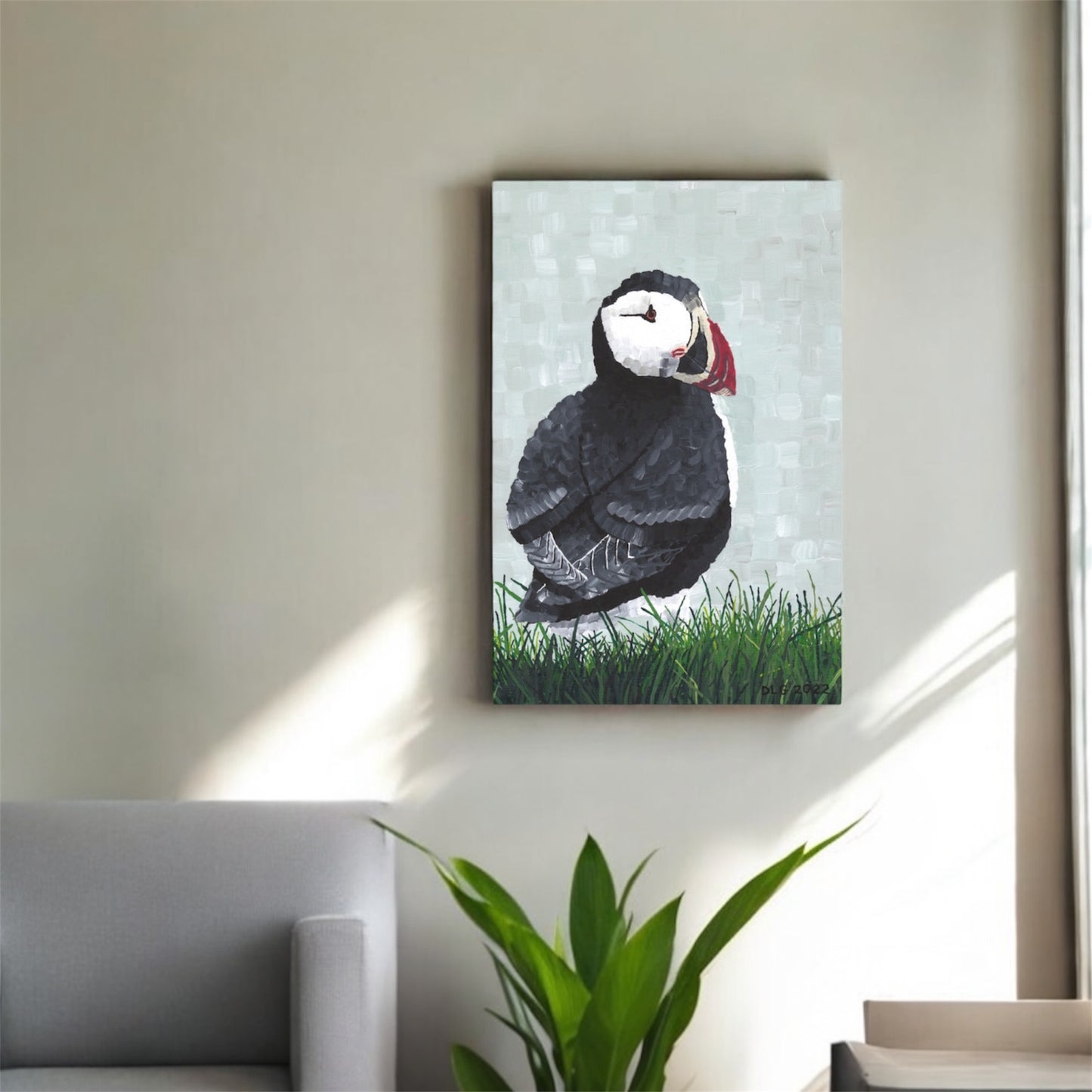 Canvas print of a puffin on a wall in a room with a plant and sofa.
