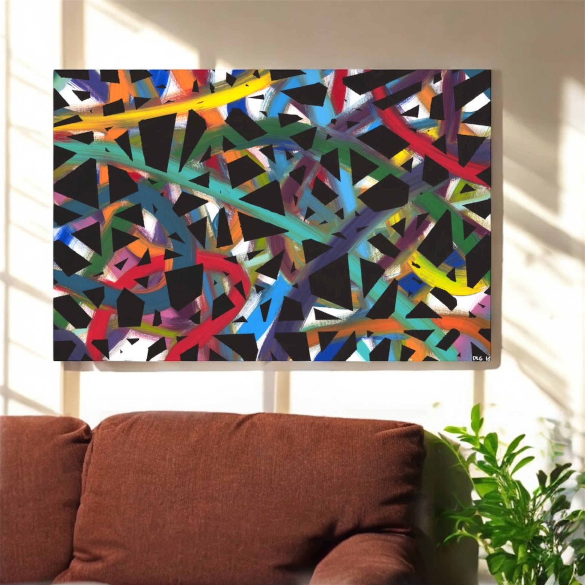 Abstract multicolored pattern on a television screen with a brown sofa and plant in the foreground.