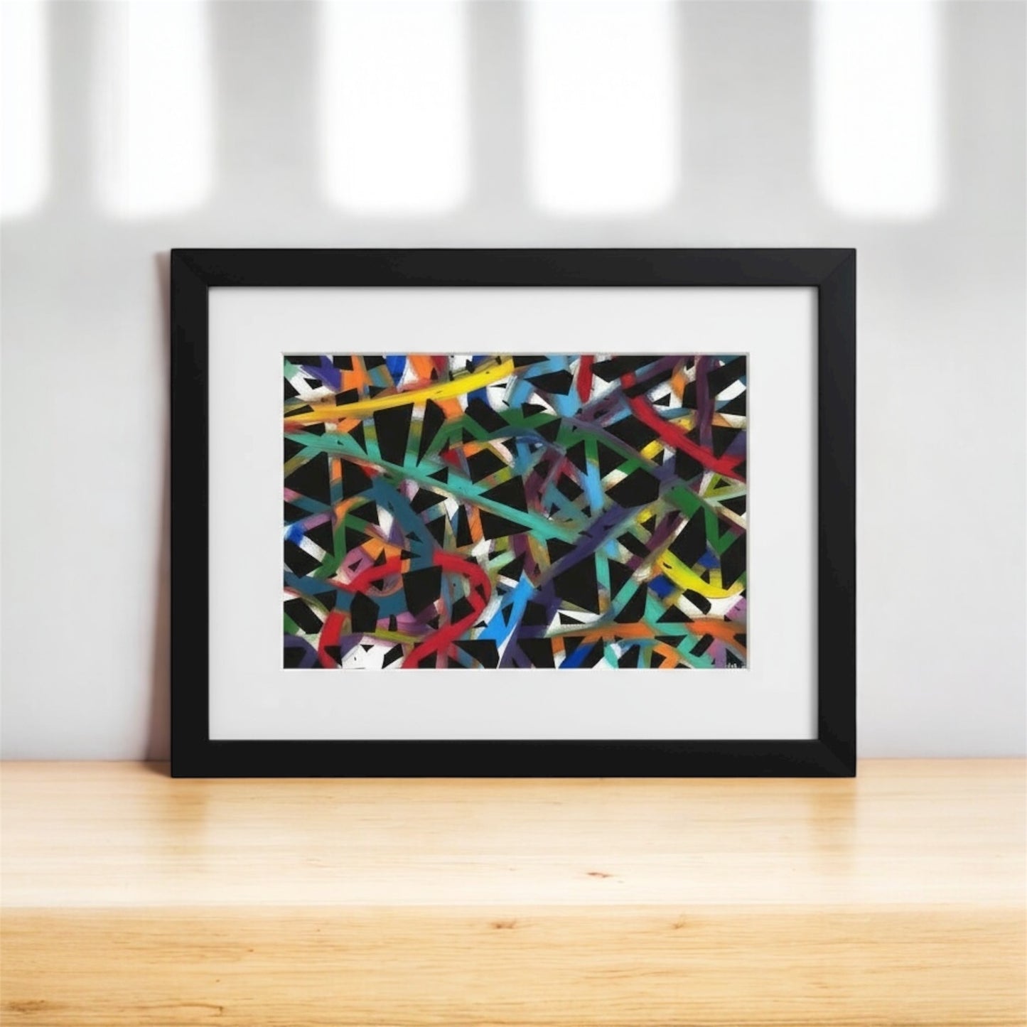 Framed abstract artwork with colorful lines on a white background