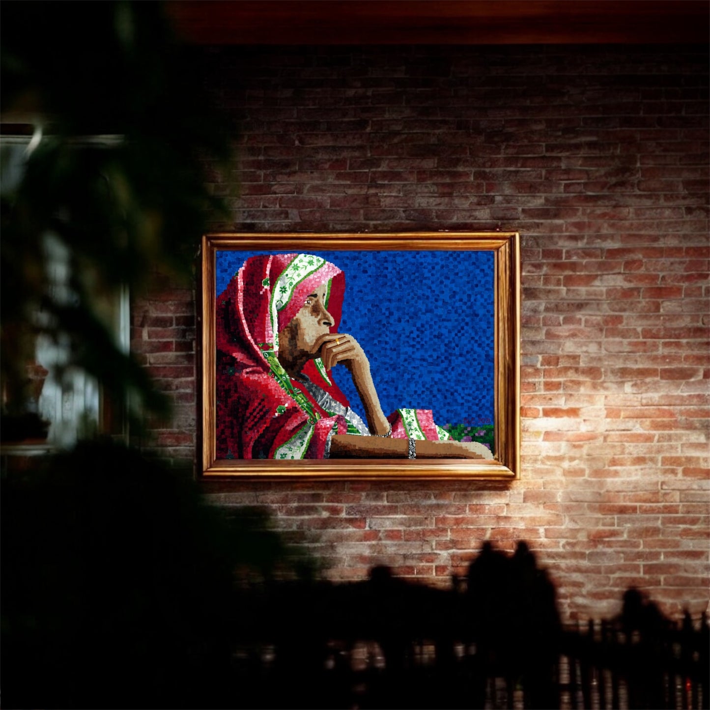 Framed artwork of a person in traditional attire on a brick wall.