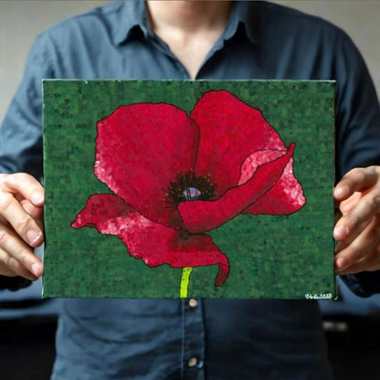 A vibrant red poppy mosaic like artwork being displayed by a man.