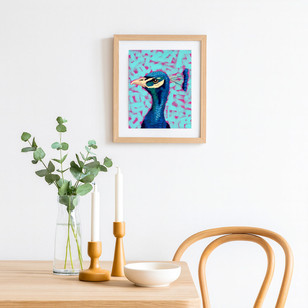 Framed artwork of a peacock on a wall above a wooden table with decor items.