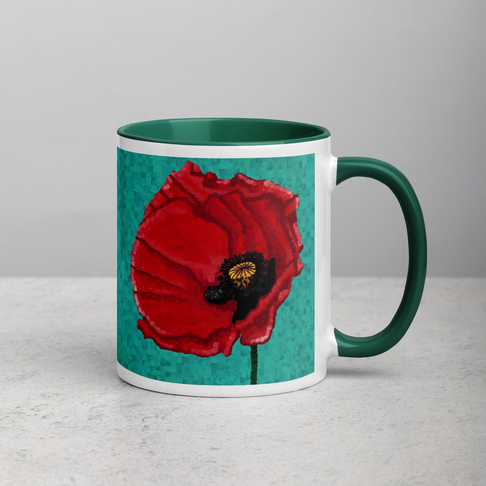 A ceramic mug with a green rim and handle, featuring a vibrant red poppy flower design on the front.
