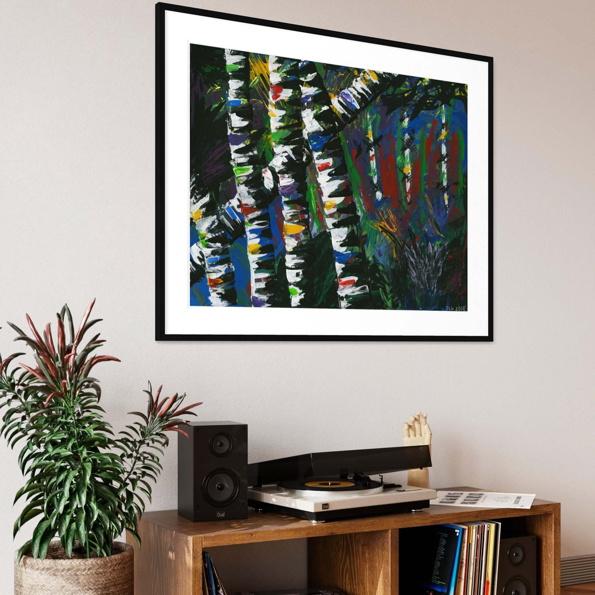 Framed Active Forest 3 print above a wooden console with a turntable and plants