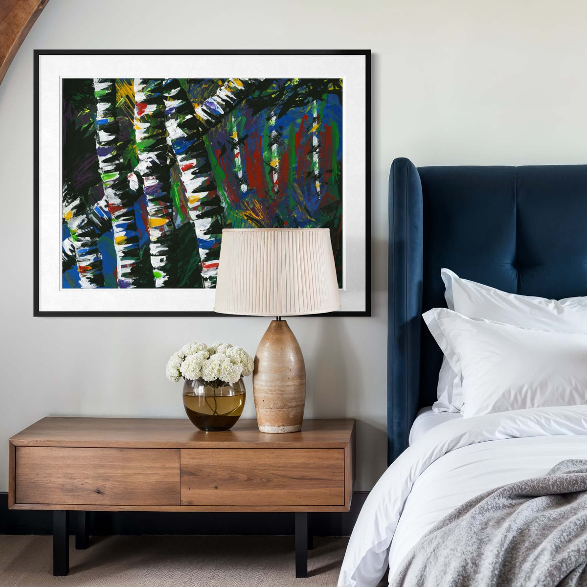 Framed Active Forest 3 print above a nightstand with a ceramic lamp and flowers