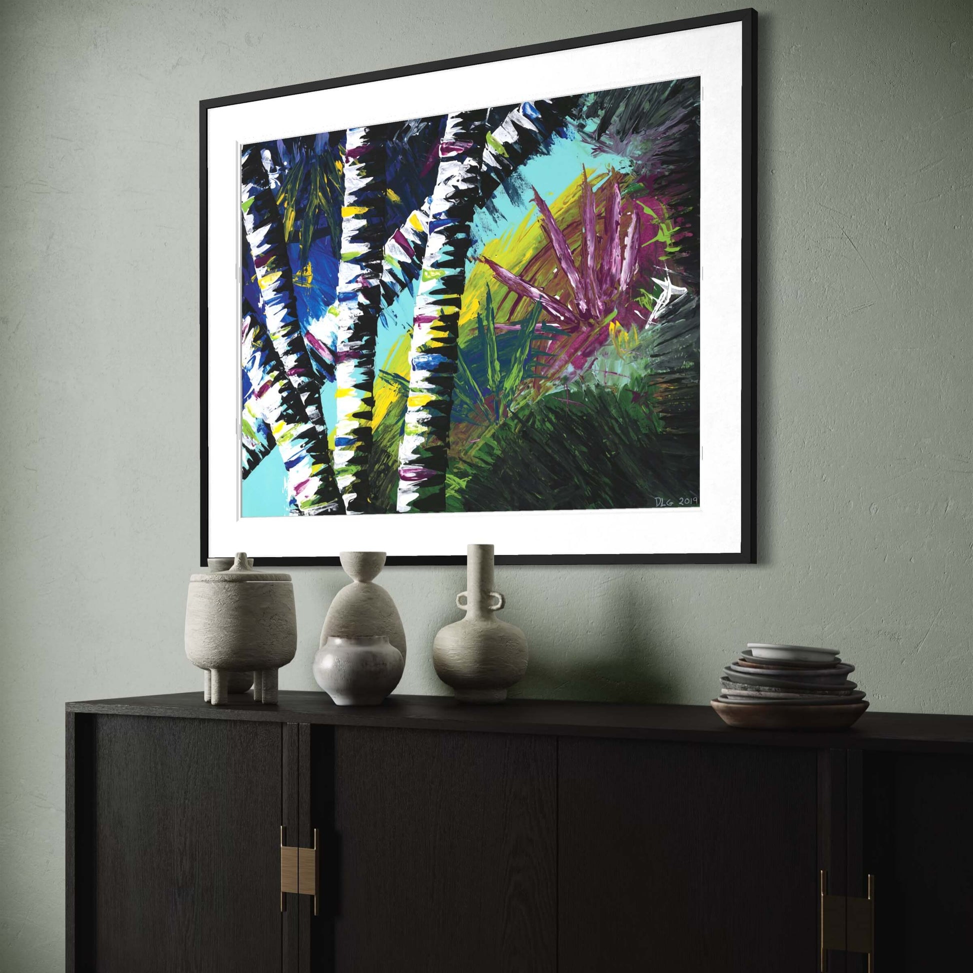 Framed Active Forest 4 print angled above a dark cabinet with ceramic vases