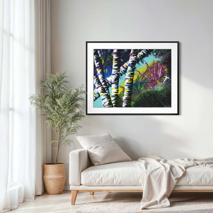Framed Active Forest 4 print above a cream daybed beside a potted plant