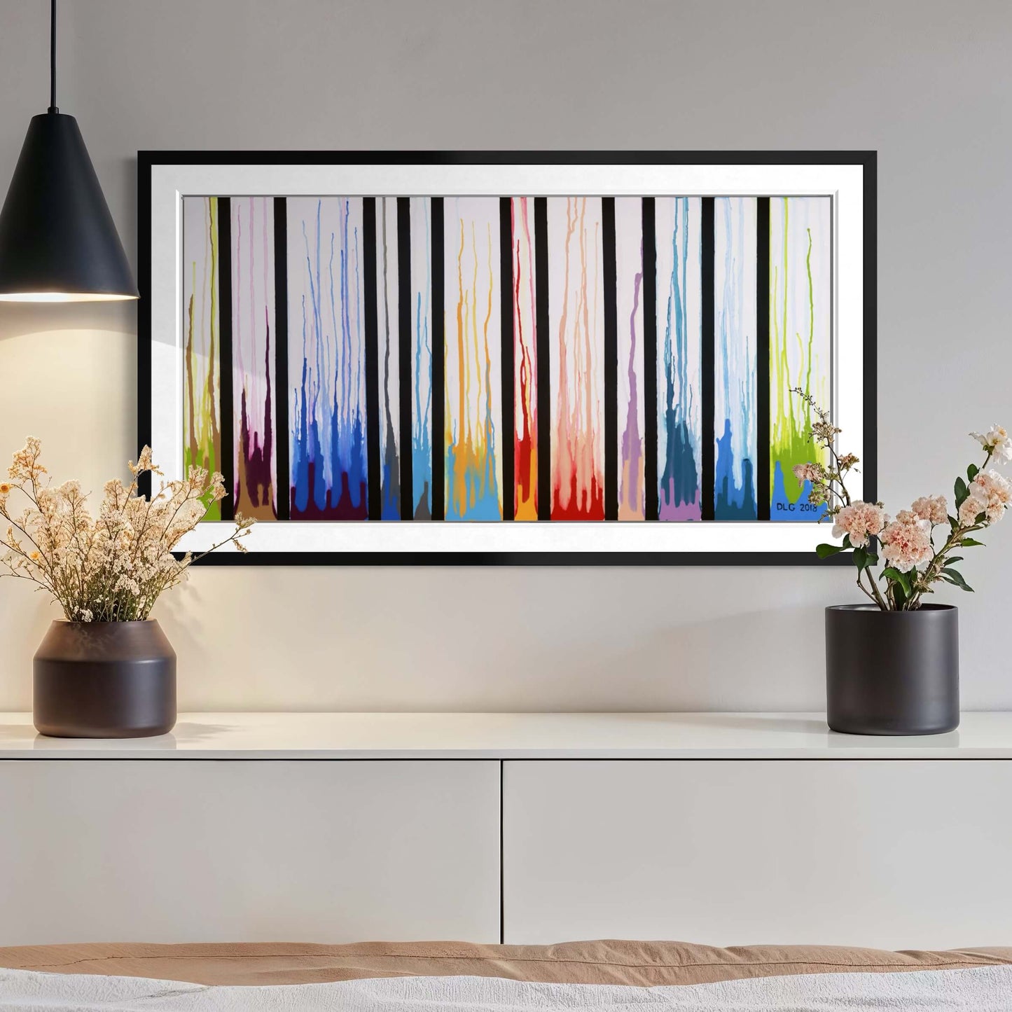 Framed Colors Rising print above a console with a pendant lamp and dried flowers