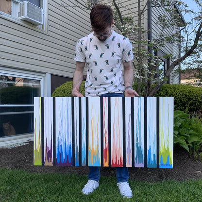Artist Dorrin Gingerich holding the original Colors Rising painting outdoors