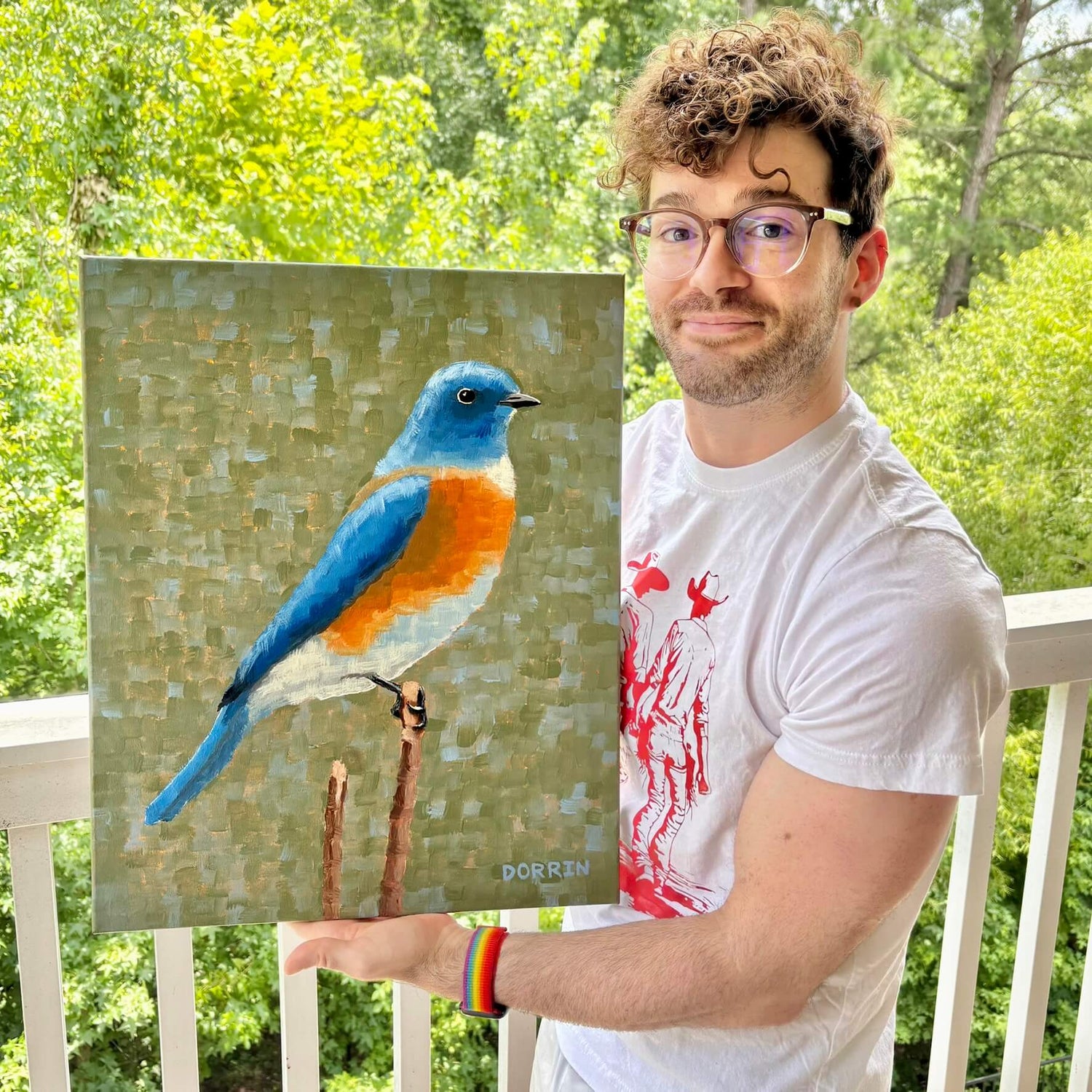 Dorrin Gingerich holding the original Eastern Bluebird painting on outdoor porch