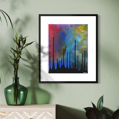A framed abstract art print featuring vibrant blue, red, yellow, and green brushstrokes with black vertical silhouettes, displayed on a sage green wall above a light wood console table with a green glass vase.