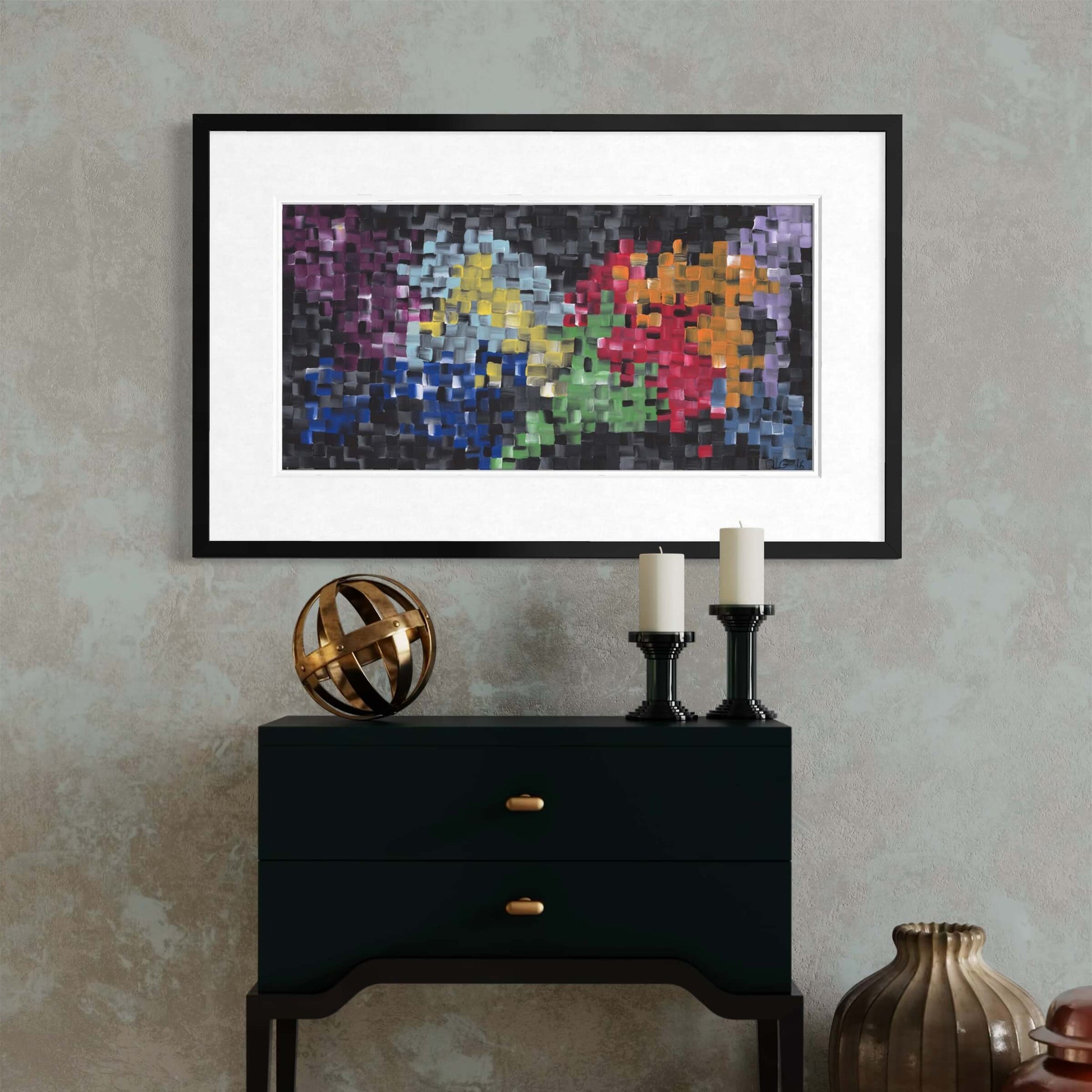 Framed First abstract print on a console with a bronze sphere and pillar candles