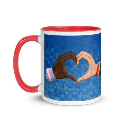 White ceramic 11 oz Loving Pride mug with red interior and handle — a vibrant LGBTQ artwork featuring two hands forming a heart, symbolizing love in art, pride in painting, and inclusion for the LGBTQ community.